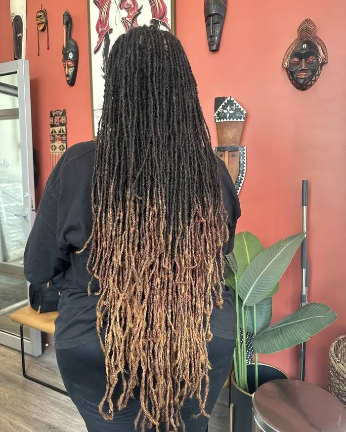 Floor-length locs against the studio's terracotta wall