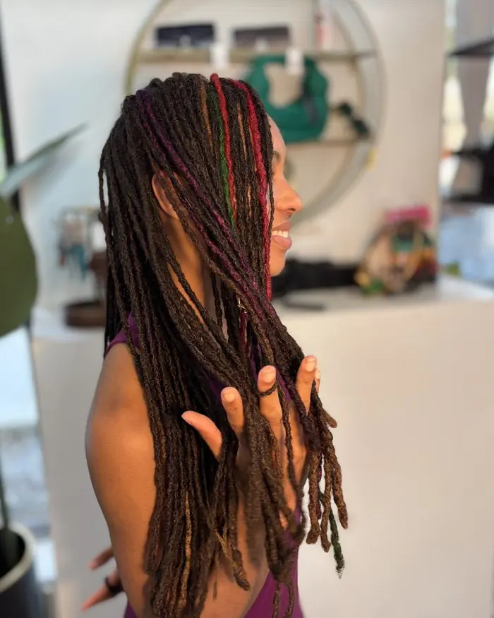 Client smiling, hands in her rasta-coloured locs