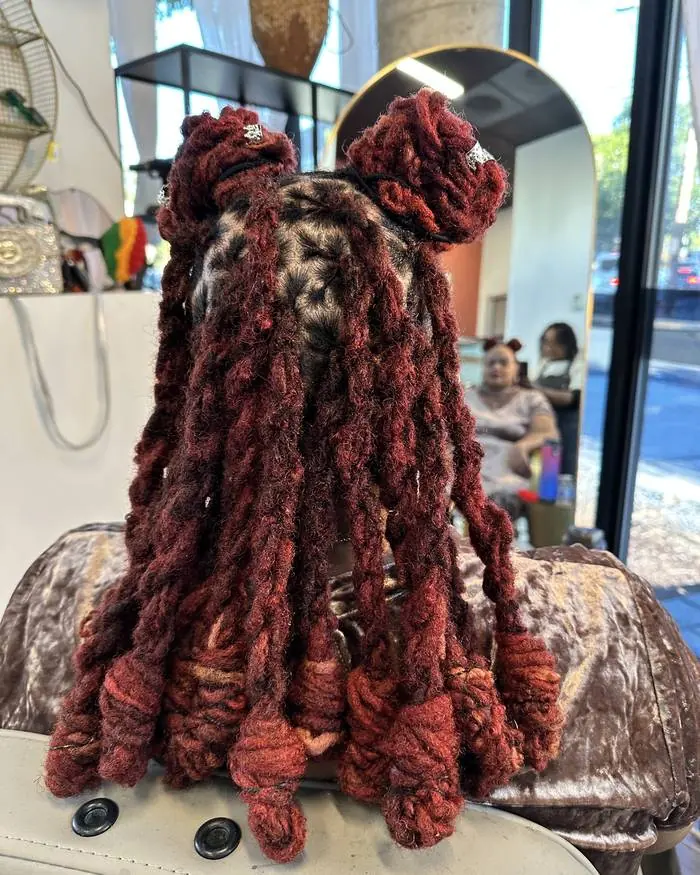 Burgundy locs set into barrel curls, back view